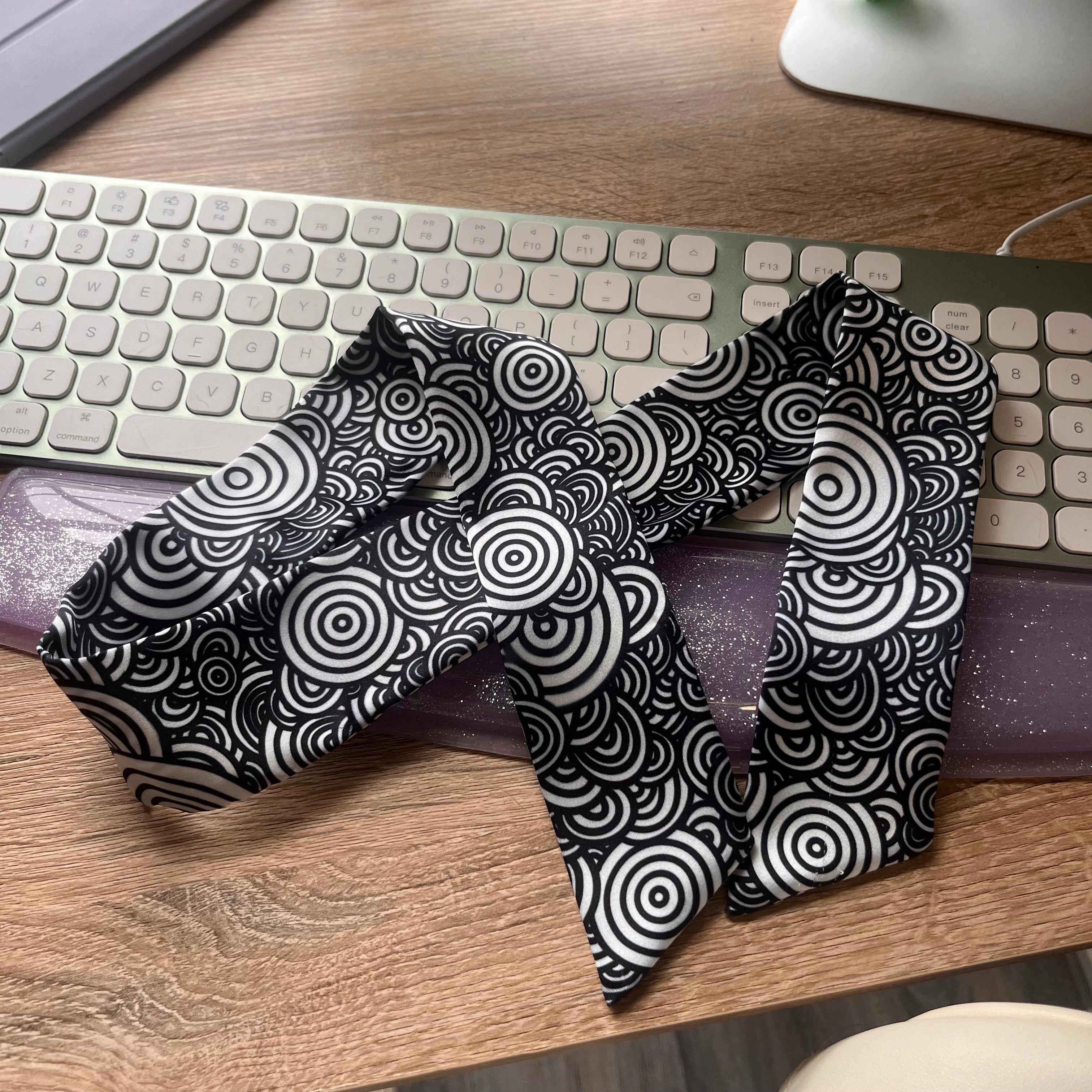 Black and white patterned fabric on a wooden desk with a keyboard in the background